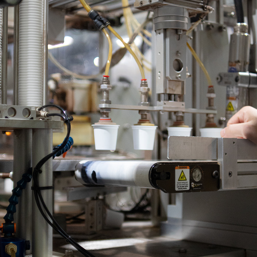 Four coffee pods coming off the machine onto a conveyor belt.