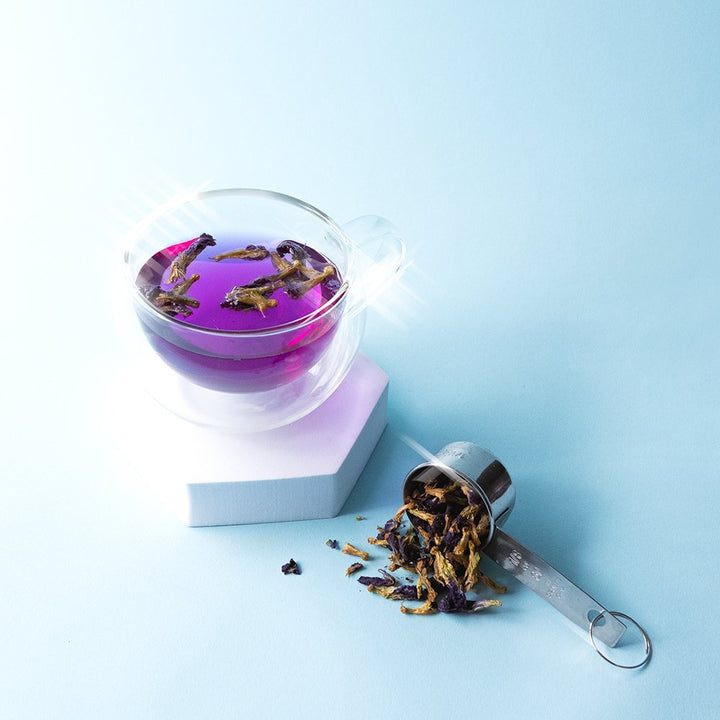 Positively Botanicals Organic Butterfly Pea Flower supplement steeped in hot water, creating a vibrant blue-purple infusion with floral aroma.