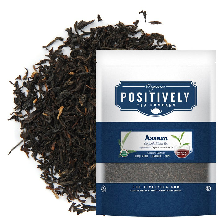 Positively Tea Company Organic Assam Black Tea in resealable pouch, surrounded by premium loose tea leaves.