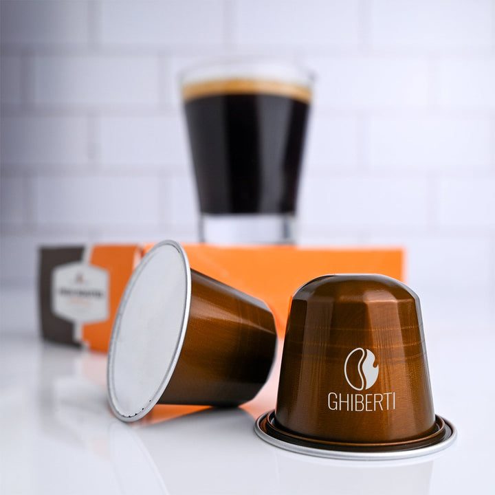 Fresh Roasted Coffee Ghiberti espresso capsules arranged with a freshly brewed shot in the background, emphasizing smooth crema, Intensity 9 roast, and tasting notes of black currant and dark chocolate.