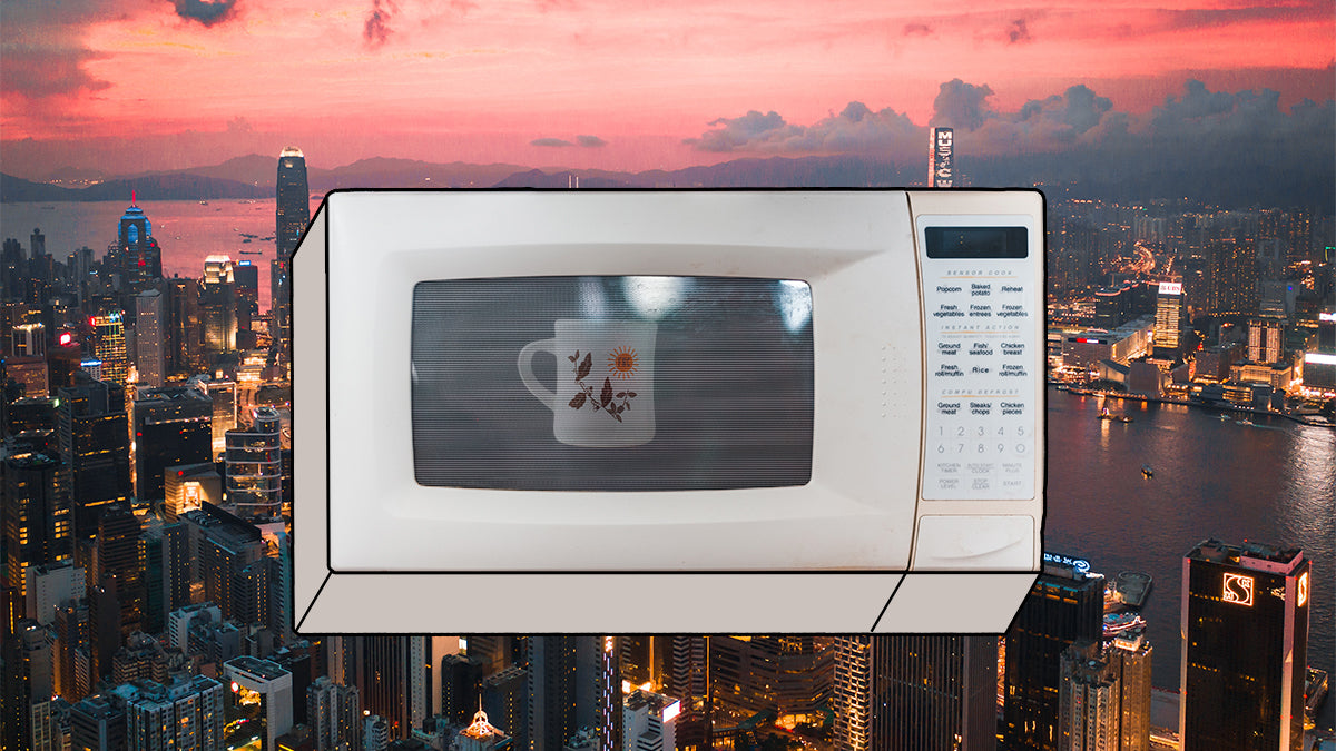 A microwave with a coffee mug inside in front of an aerial photo of the Hong Kong skyline.