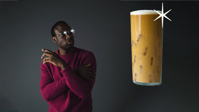 Millennial looking longingly at a glass of frosty cold brew coffee.