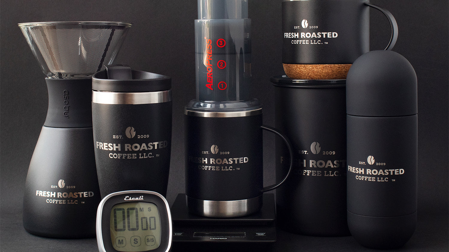 A variety of stainless-steel Fresh Roasted Coffee gear, including coffee storage canisters, insulated mugs, and pour overs.