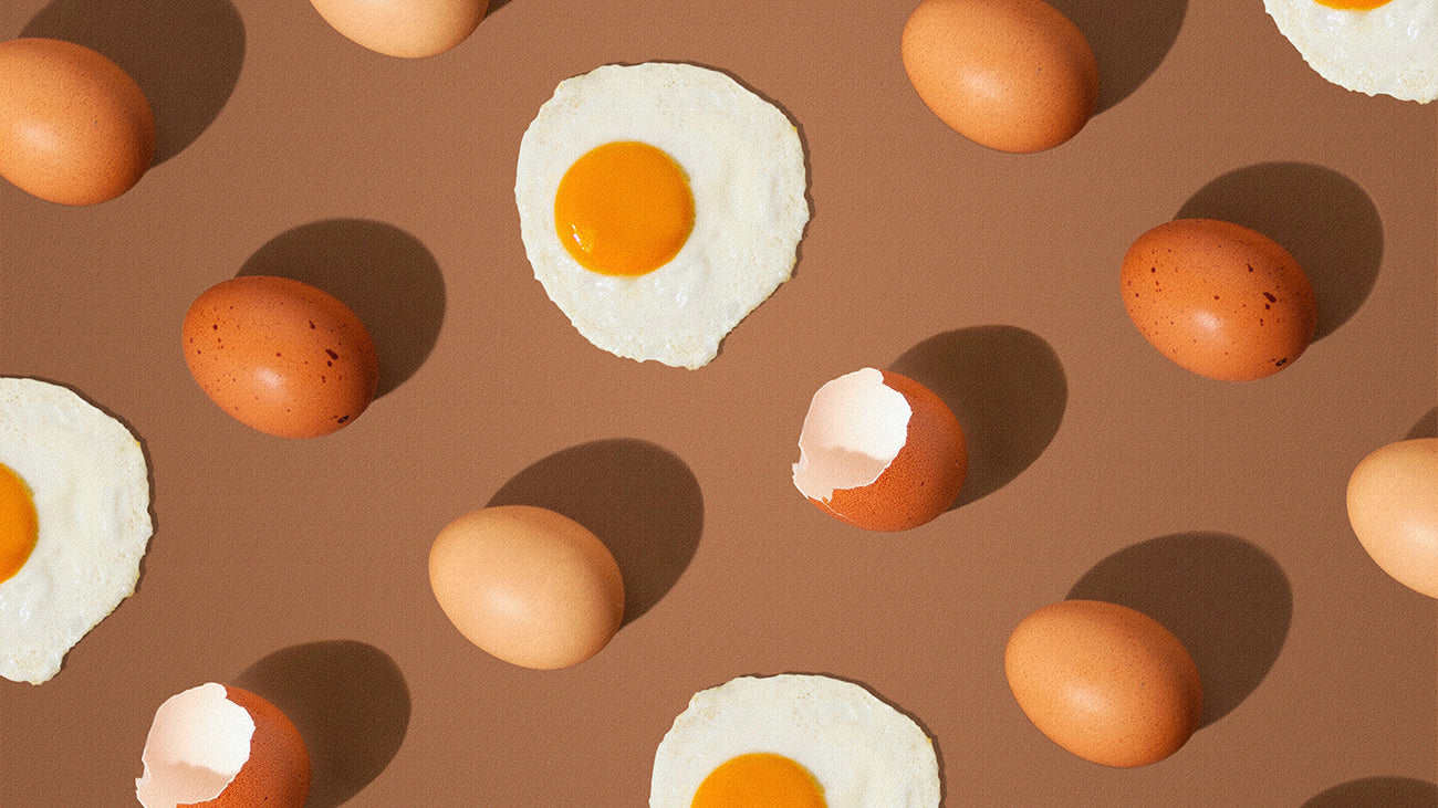 A flat lay image of whole eggs, eggshells, and fried eggs.