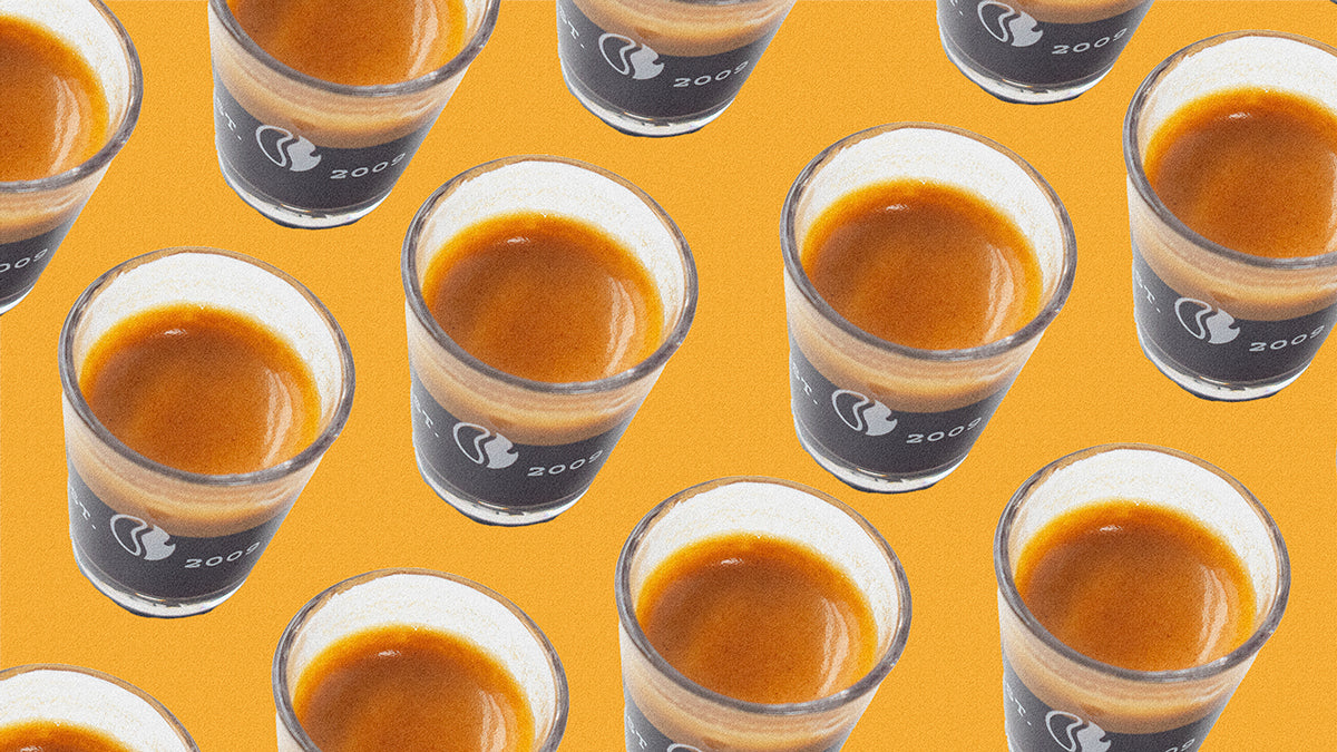 Espresso shots in shot glasses on an orange background.