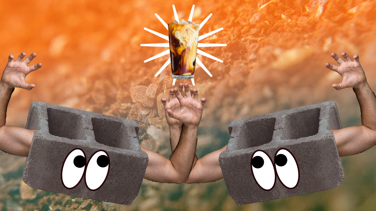 Two cinderblocks with arms looking at a cold brew coffee against a background of coffee grounds.