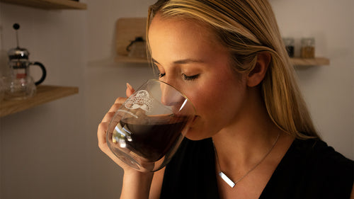 Woman sipping from a double-walled mug of coffee.