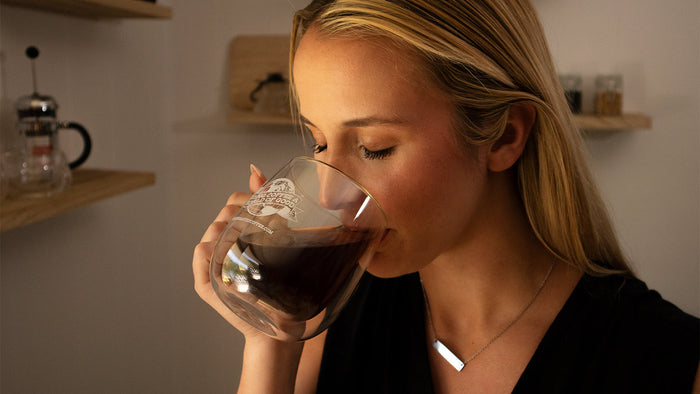 Woman sipping from a double-walled mug of coffee.