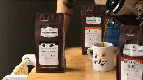 Three bags of artisan blend coffee around a carafe pouring hot coffee into a diner mug.