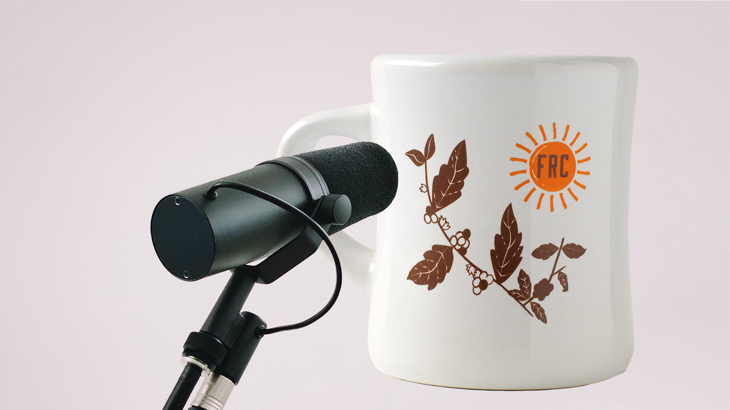 A coffee mug behind a podcasting microphone.