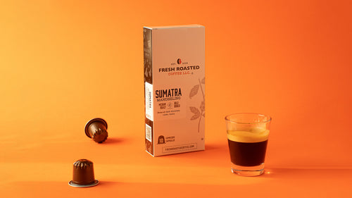 A tall box of Sumatra espresso capsules on an orange background next to a shot of espresso.