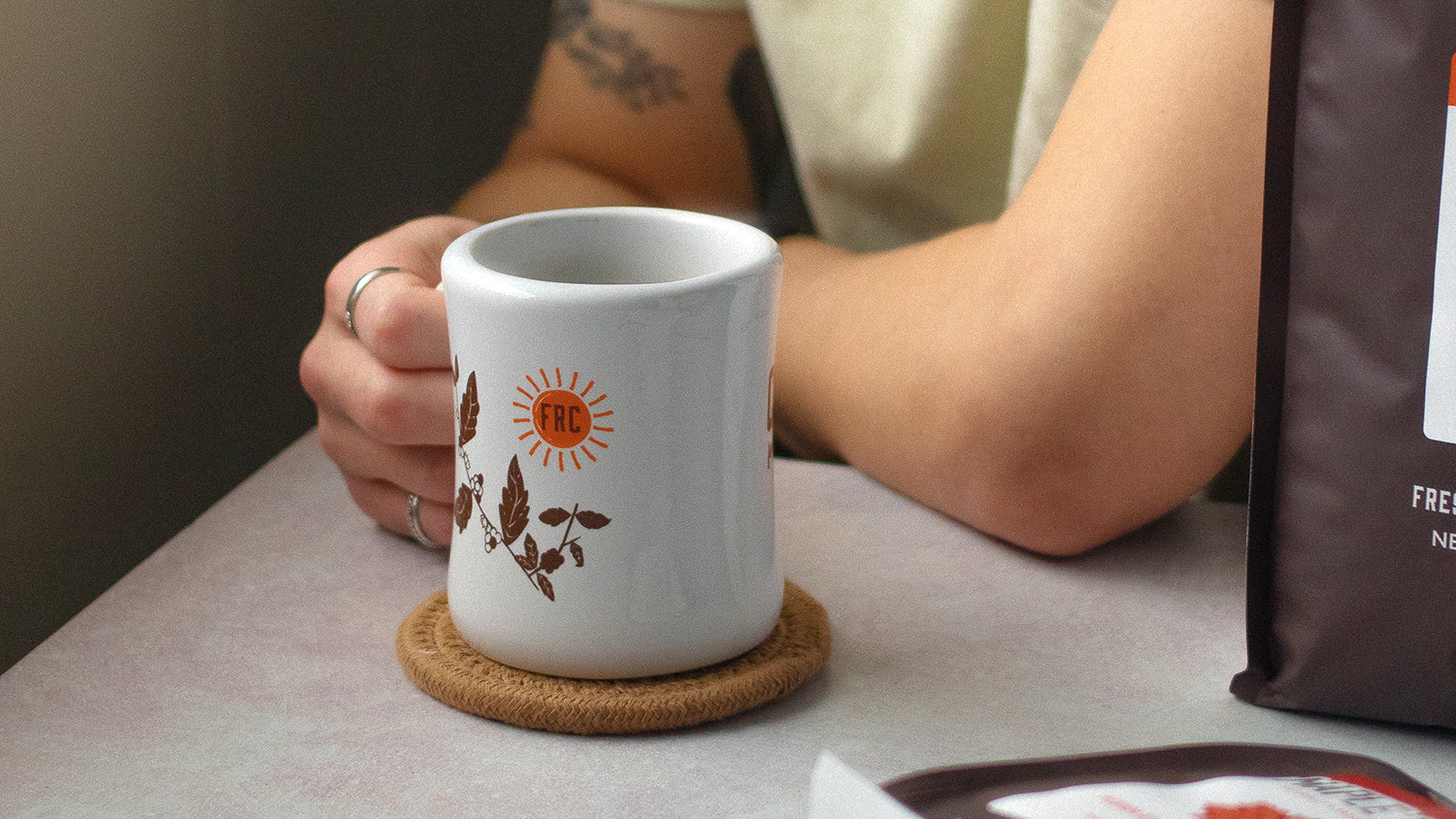 Person holding diner mug resting on a table.
