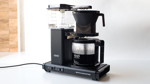 A Technivorm Moccamaster automatic coffee maker on a white countertop.