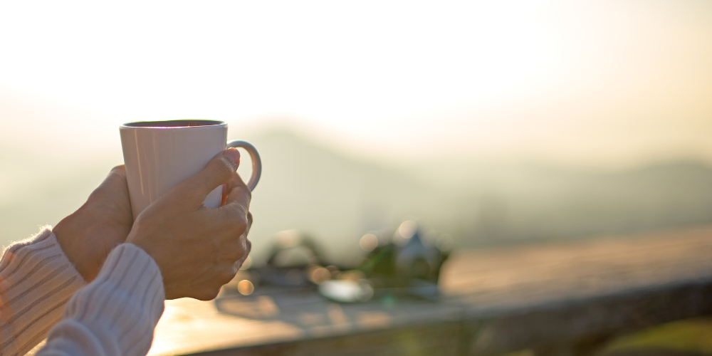 Summer view with hands holding a mug
