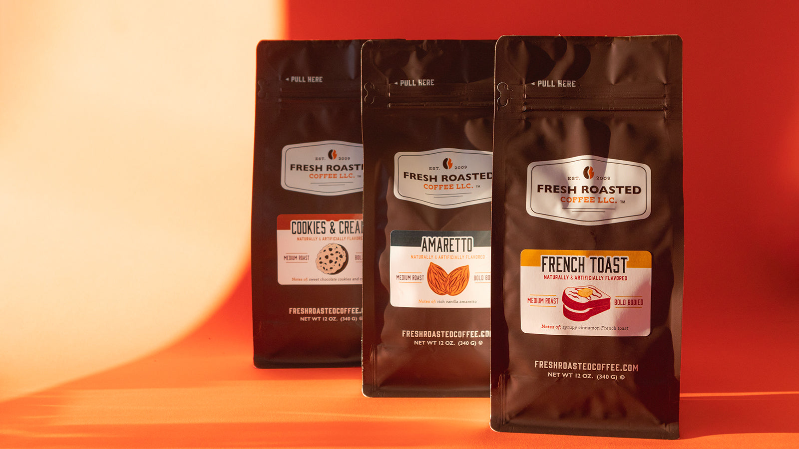 Three bags of flavored coffee on an orange background around sunrise.