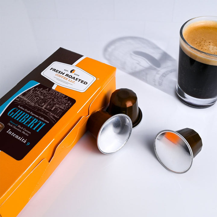 Fresh Roasted Coffee LLC Ghiberti Italian Craft Espresso capsules, 10-count box with capsules next to a freshly brewed espresso, showcasing Intensity 9 dark roast with black currant and dark chocolate notes.