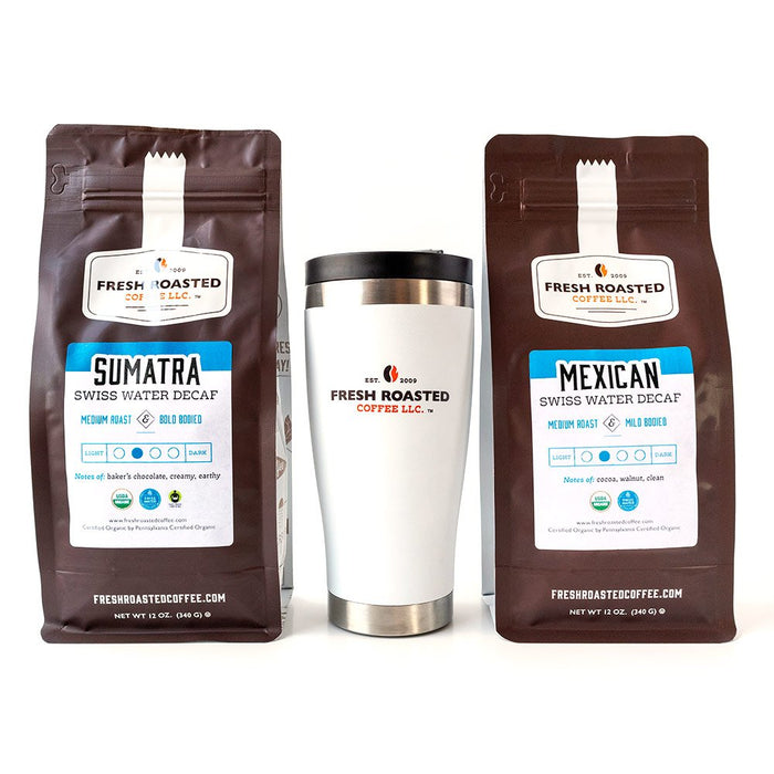 A bag of Organic Swiss Water Decaf Sumatra coffee, a bag of Organic Swiss Water Decaf Mexican coffee, and a white Fresh Roasted Coffee travel mug.